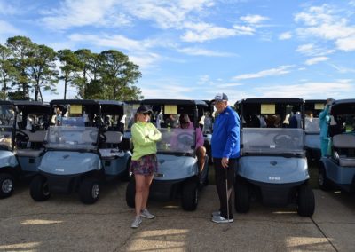 friends chatting around golf carts at the coastal alabama couples classic